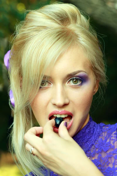 Woman in violet fashion dress eating grape — Stock Photo, Image