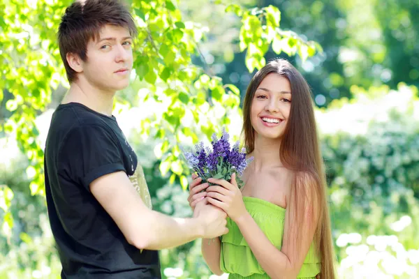 man presenting blue flowers to a woman