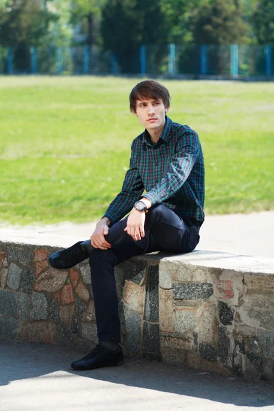 Молодой человек сидит на улице — стоковое фото
