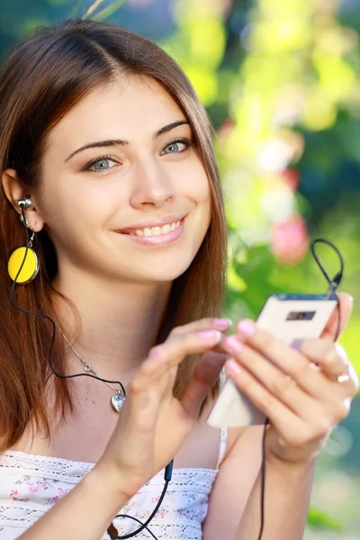 Mujer joven usando un teléfono inteligente para escuchar música —  Fotos de Stock