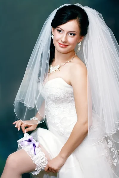 Beautiful bride putting on the garter — Stock Photo, Image