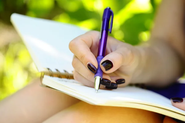 Caderno, caneta e mão feminina de perto . Imagem De Stock