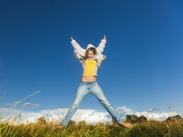 Flickan hoppar högt i fältet — Stockfoto