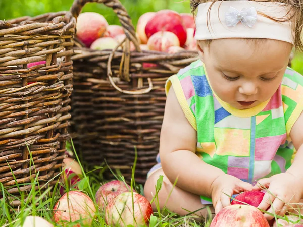 Kleines Mädchen mit einem Korb voller roter Äpfel — Stockfoto