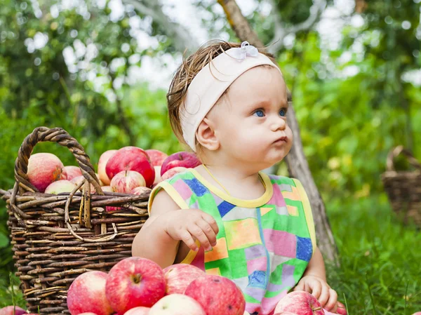 Kleines Mädchen mit einem Korb voller roter Äpfel — Stockfoto
