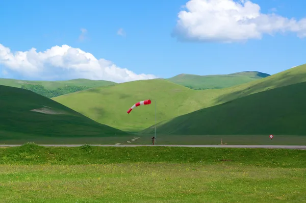 Wind-sleeve on green plateau in mountains in Italy — Stock Photo, Image