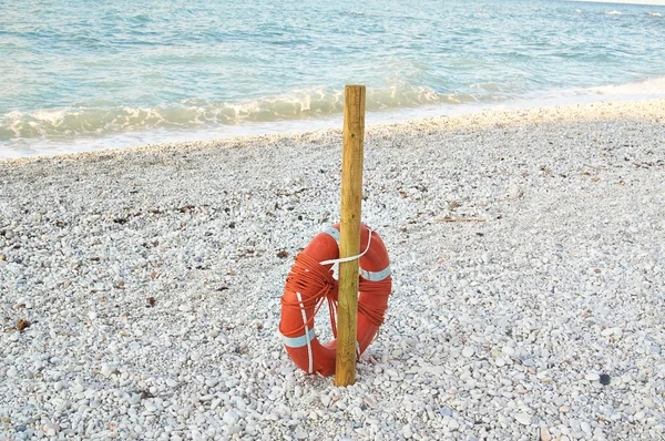 Bouée de sauvetage rouge attachée au poteau sur la plage en été — Photo