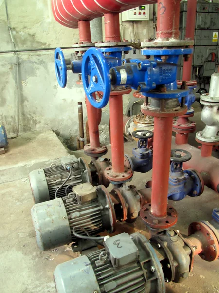 Valves with blue handles and old pumps embedded in the installat — Stock Photo, Image