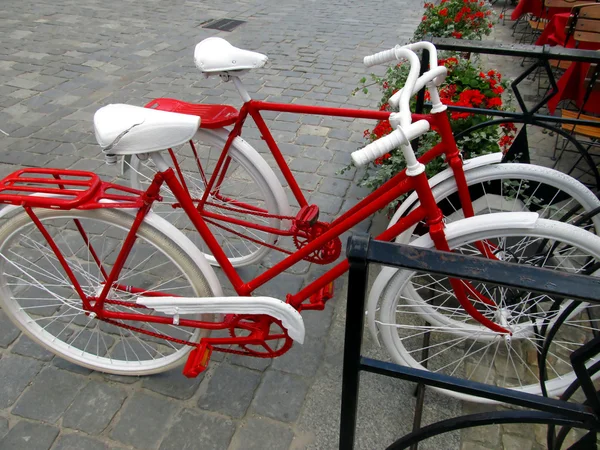 Duas bicicletas para mulheres e homens, pintadas de branco e vermelho em pé em um rack — Fotografia de Stock