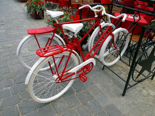 Duas bicicletas para mulheres e homens, pintadas de branco e vermelho em pé em um rack — Fotografia de Stock