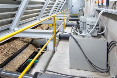 Hidrolik silindirler biyokütle kazıyıcı besleyiciyi çöp kutusundan kazıyıcıya iter.