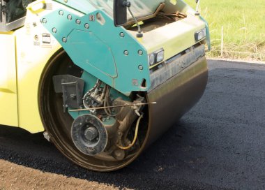 Yol silindiri, toprak bir yolda asfaltın ilk katmanını sıkıştırıyor.