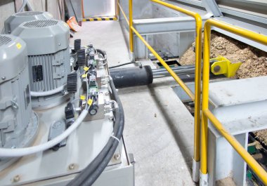 Hidrolik silindirler biyokütle kazıyıcı besleyiciyi çöp kutusundan kazıyıcıya iter.