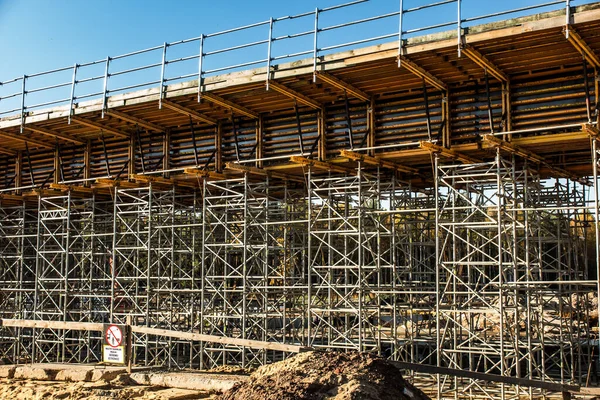 Arka plan olarak karayolu üzerinde bir Üstgeçit altında inşa inşaat iskele. İşaret - makine mobil, dikkat