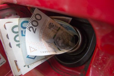 Banknotlar, Polonya parası, kırmızı bir arabanın benzin deposunda Polonyalı zloti. Yakıt fiyatlarındaki artış yakıt depolarına para çekilmesine neden oluyor..