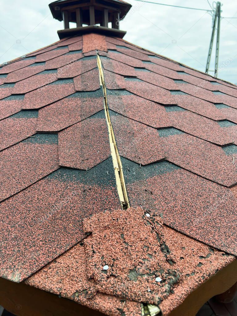 damage to the roof covering made of shingle on the gazebo in the garden