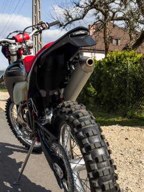 Güneşli bir havada asfalt bir yolda kırmızı bir off-road motosikleti..