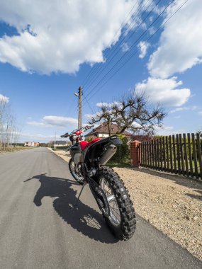 Güneşli bir havada asfalt bir yolda kırmızı bir off-road motosikleti..