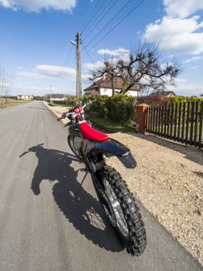 Güneşli bir havada asfalt bir yolda kırmızı bir off-road motosikleti..