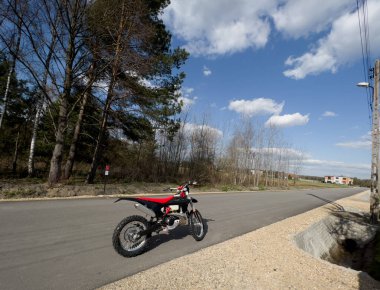 Güneşli bir havada asfalt bir yolda kırmızı bir off-road motosikleti..