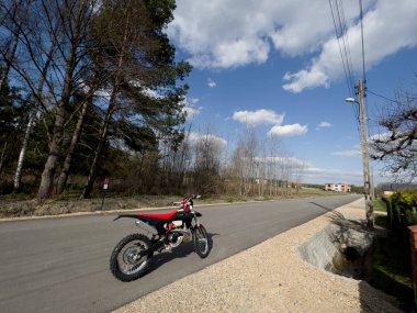 Güneşli bir havada asfalt bir yolda kırmızı bir off-road motosikleti..