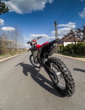 Güneşli bir havada asfalt bir yolda kırmızı bir off-road motosikleti..