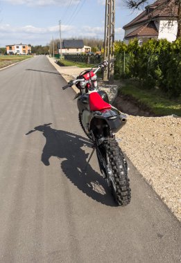 Güneşli bir havada asfalt bir yolda kırmızı bir off-road motosikleti..