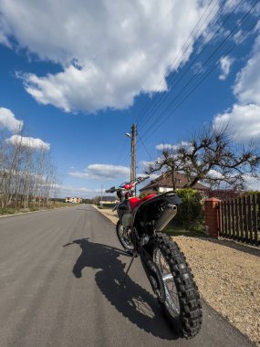 Güneşli bir havada asfalt bir yolda kırmızı bir off-road motosikleti..
