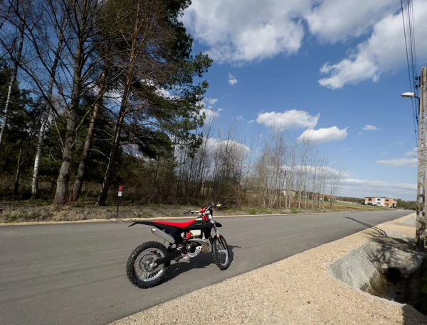Güneşli bir havada asfalt bir yolda kırmızı bir off-road motosikleti..
