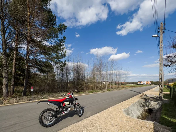 Güneşli bir havada asfalt bir yolda kırmızı bir off-road motosikleti..