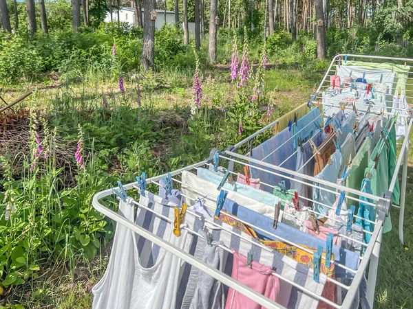 Drying of linen and other items of clothing after washing in a dryer placed in a forest clearing near the house on a sunny day.