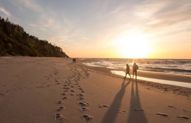 Bahar, gün batımında boş Baltık Denizi sahillerinde bir tür rahatlama olarak yürür..