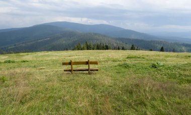 A bench in a meadow in front of the mountain shelter in Hala Rysianka in Beskid Zywiecki in Poland, where you can sit and admire the picturesque views of the surrounding areas.
