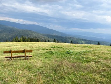 A bench in a meadow in front of the mountain shelter in Hala Rysianka in Beskid Zywiecki in Poland, where you can sit and admire the picturesque views of the surrounding areas.
