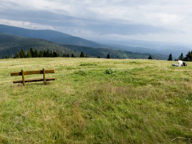 A bench in a meadow in front of the mountain shelter in Hala Rysianka in Beskid Zywiecki in Poland, where you can sit and admire the picturesque views of the surrounding areas.
