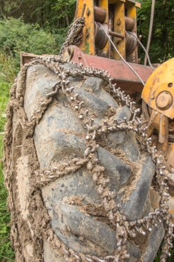 Chain on the wheels of a skidder, i.e. a tractor for skidding wood in difficult mountain terrain and with earthen ground.