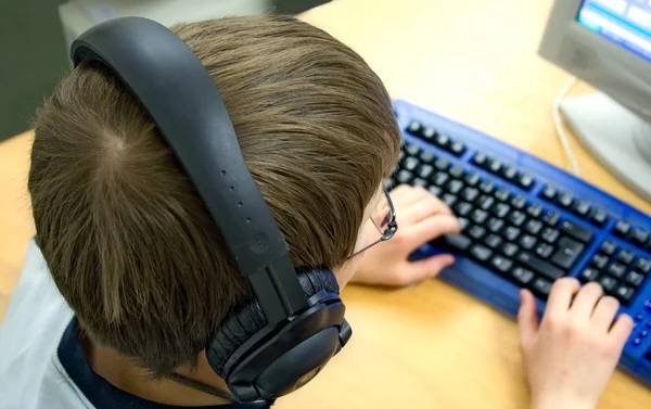 Компьютерный ребенок с наушниками Стоковое Фото