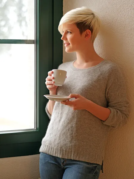 Tittar ut genom ett fönster som dricker kaffe — Stockfoto