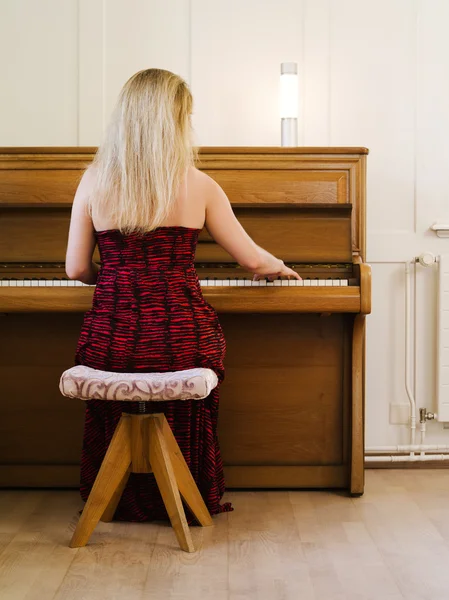 Blond kobieta gra na pianinie w domu — Zdjęcie stockowe