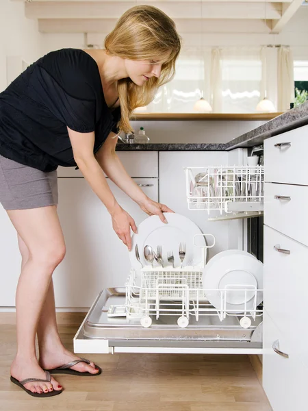 Женщина опустошает посудомоечную машину — стоковое фото