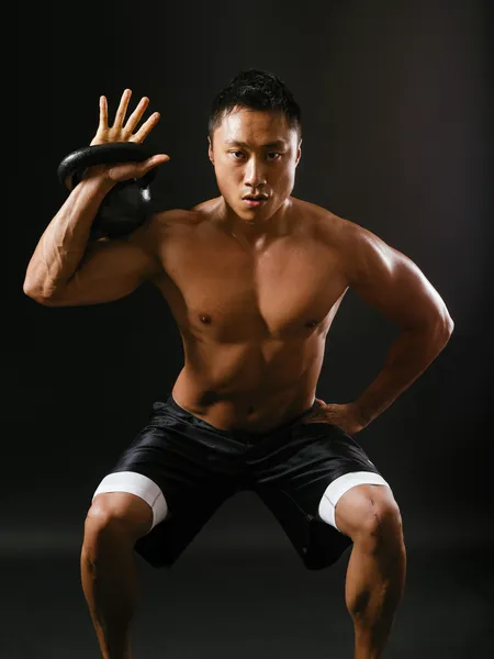 Holding a kettlebell and doing squats — Stock Photo, Image