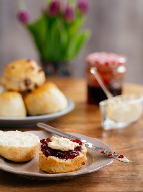 Scones prepared with clotted cream and jam clipart