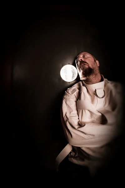 Crazy person in a cell wearing a straitjacket — Stock Photo, Image