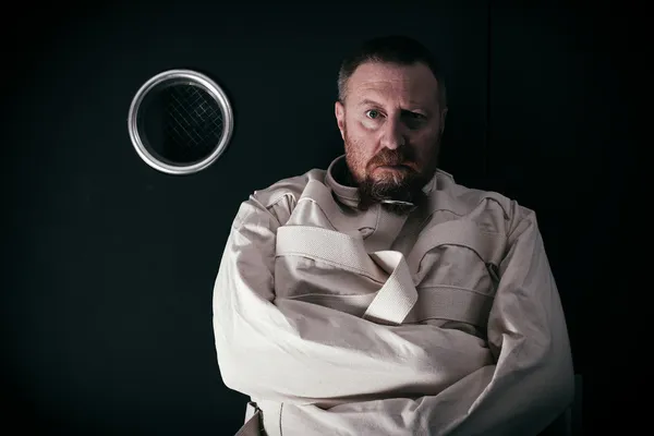 Insane man in a cell wearing a straitjacket — Stock Photo, Image