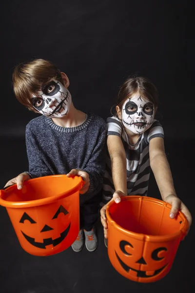 Børn Med Kranium Makeup Holder Græskar Spande Til Halloween - Stock-foto