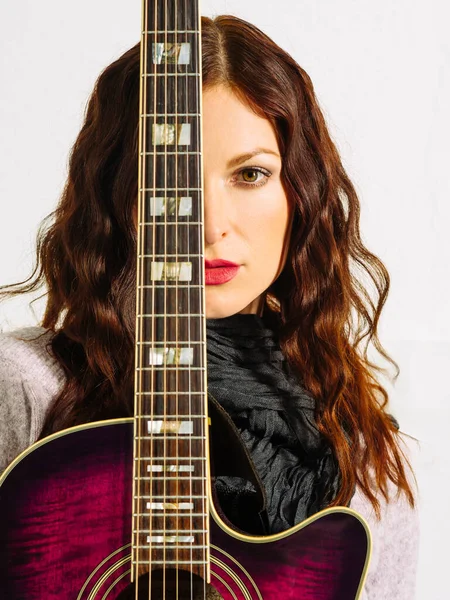 若いです美しいです赤毛女性保持Aアコースティックギター上の彼女の顔 — ストック写真