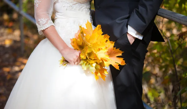 Sposo e sposo in possesso di un bouquet di foglie d'oro — Foto Stock