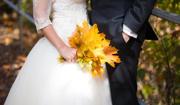 Жених и невеста держат букет из золотых листьев — стоковое фото