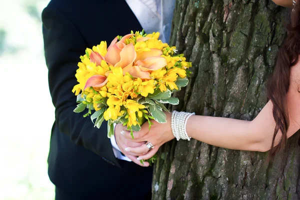 Joven pareja casada cogida de la mano con ramo de boda —  Fotos de Stock