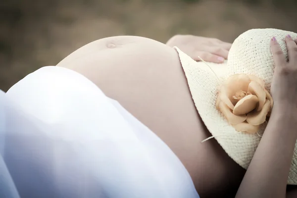 Mujer embarazada sosteniendo un sombrero en su vientre — Foto de Stock